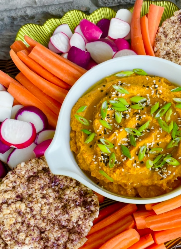Image displays a grazing platter with Thai carrot hummus along with radishes, carrots, and rice cakes for dipping.